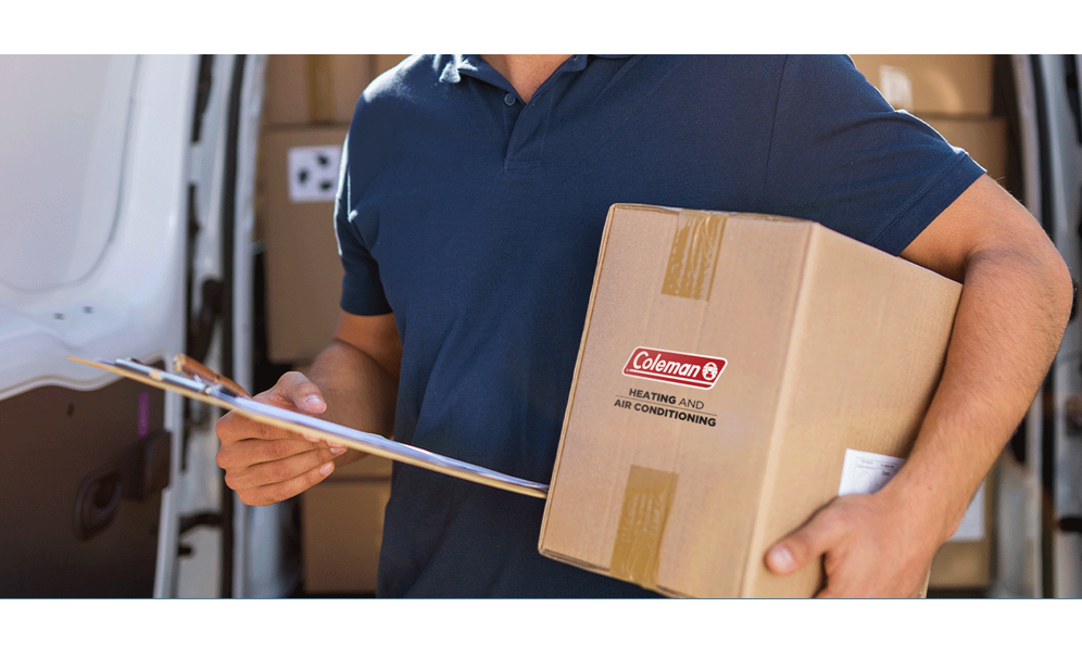 Man holding a cardboard box with the Coleman logo under his arm 